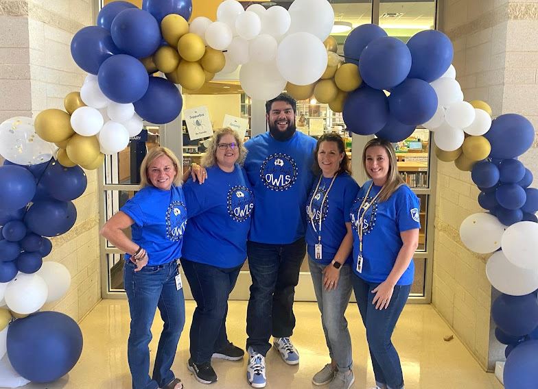 Specials block teachers pose under a balloon arch on the first day of school